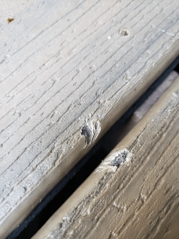 Damaged composite decking showing wear and tear, highlighting the difficulty of repairing with screw fixings
